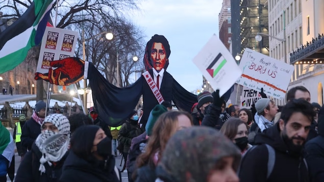 Mga taong nagpoprotesta na may hawak na effigy ni Trudeau, banners at watawat ng Palestine.