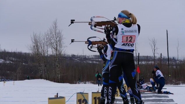 Des fondeuses participant à l'épreuve de biathlon s'apprêtent à tirer sur leurs cibles lors des Jeux d'hiver de l'Arctique de Wood Buffalo, en Alberta, le vendredi 3 février 2023.