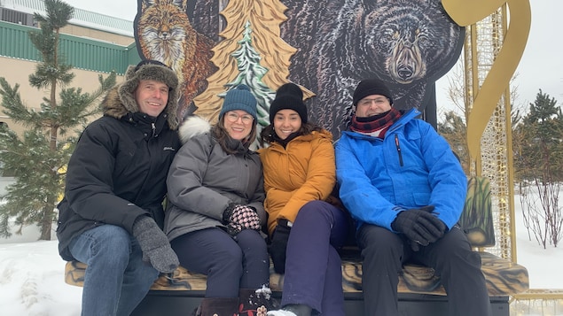 De gauche à droite : Richard Marion, Julie Plourde, Matisse Harvey et Marc-Éric Bouchard posent, souriants, au pied d'une image arborant un renard et un ours, en marge des Jeux d'hiver de l'Arctique de Wood Buffalo, en Alberta, le vendredi 3 février 2023.
