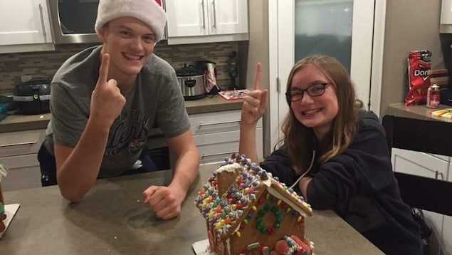 Logan Hunter et Abbie Cannon posent un doigt en l'air, accoudés sur la table où se trouve la maison en pain d'épice qu'ils ont faite pour Noël. Logan Hunter et Abbie Cannon posent un doigt en l'air, accoudés sur la table où se trouve la maison en pain d'épice qu'ils ont faite pour Noël.