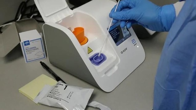 Une unité de test rapide avec la main d'un spécialiste tenant un écouvillon nasal.