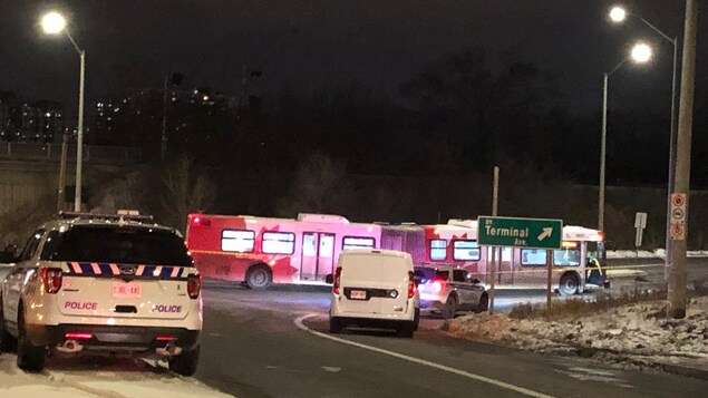 Un autobus articulé et des voitures de police la nuit.
