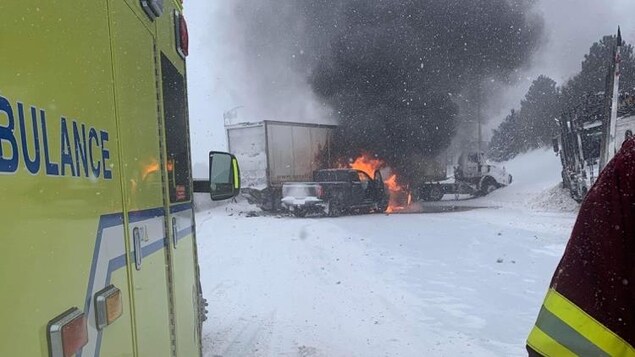 Un camion en travers de l'autoroute avec une camionnette en feu.