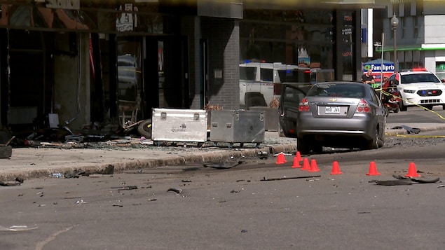 Scène d’accident sur le boulevard Charest Ouest, à Québec. On aperçoit un véhicule de police, une voiture accidentée de couleur grise, des éclats de verre, de plastique et de métal ainsi que de petits cônes orange déposés sur la chaussée.