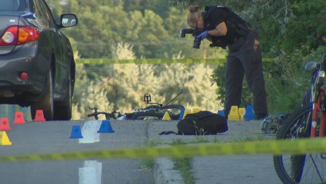 Une enquêteuse prend des photos la scène après une collision entre une voiture et un cycliste, boulevard Jeanne D'Arc, à Ottawa.
