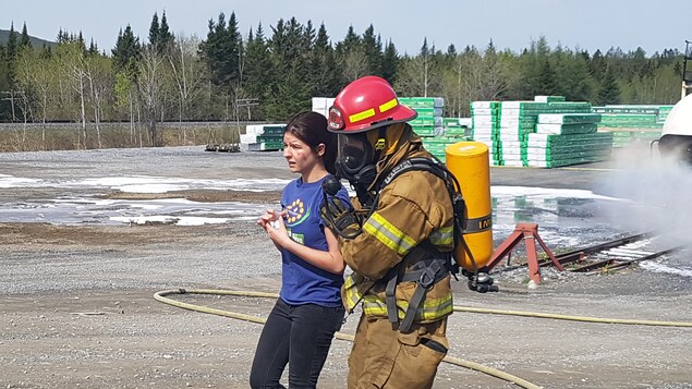 Une jeune fille recouverte de faux sang est escortée par un pompier portant un masque à oxygène.
