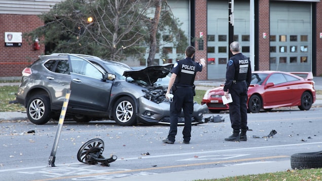 Deux policiers du SPVM se parlent près de la camionnette accidentée.