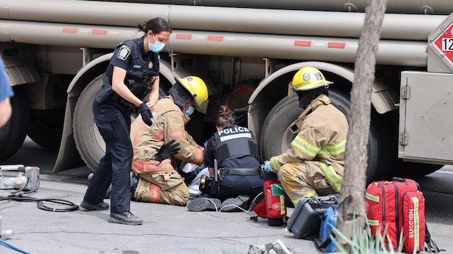 Deux pompiers et deux policières assistent la victime d'un accident.