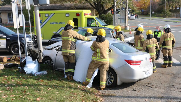 Une dizaine de pompiers interviennent sur une voiture accidentée, à une intersection.