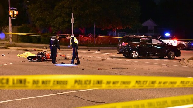 Two police officers at night in an intersection with a crashed motorcycle and SUV.