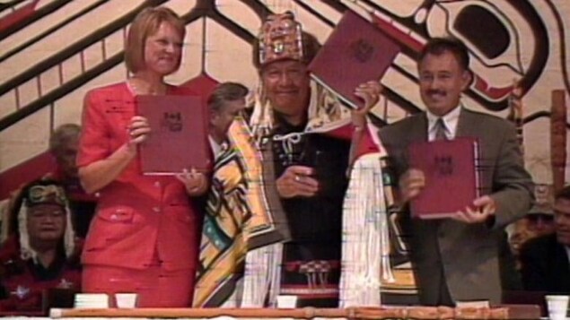 Tres personas muestran documentos.