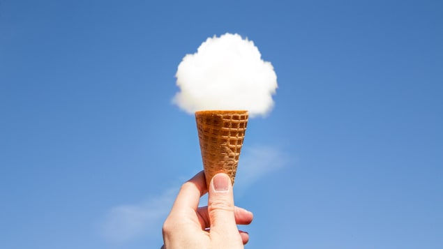 Image originale représentant un homme tenant un cornet de glace dans le ciel, avec un nuage rond au sommet du cornet en biscuit.