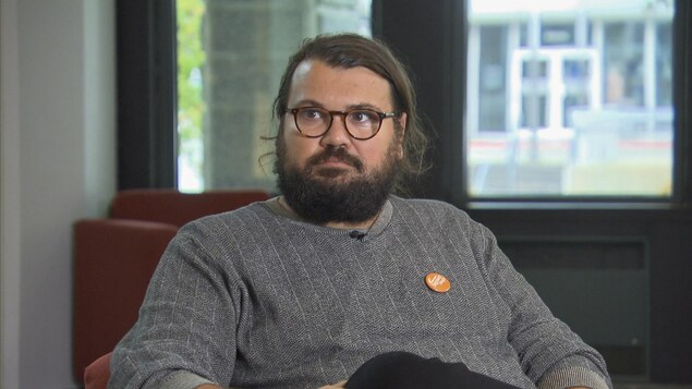 Adis Simidzija assis dans un fauteuil durant une entrevue.