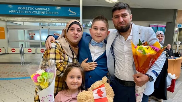 The Kharsa family poses for their first-ever photo as a family. Adnan Kharsa, 11, was separated from his parents by the Syrian war in 2017. His sister, Sham, 5, wasn't born until a year later. They posed for this family photo after reuniting at Saskatoon International Airport on Wednesday. (Bonnie Allen/CBC)