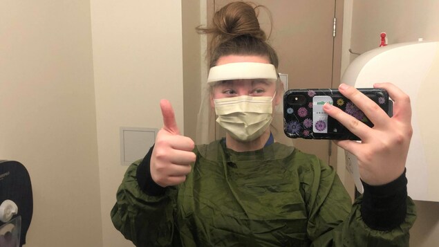 Une jeune femme en habits de protection prend un égoportrait.