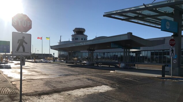 L'extérieur de l'aéroport de Saskatoon par un beau soleil. Aucune voiture ne circule et aucune personne à l'horizon.