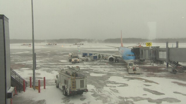 Plusieurs véhicules et un avion près d'un piste de l'aéroport Jean-Lesage de Québec lors d'une journée de tempête en janvier 2018 Plusieurs véhicules et un avion près d'un piste de l'aéroport Jean-Lesage de Québec lors d'une journée de tempête en janvier 2018