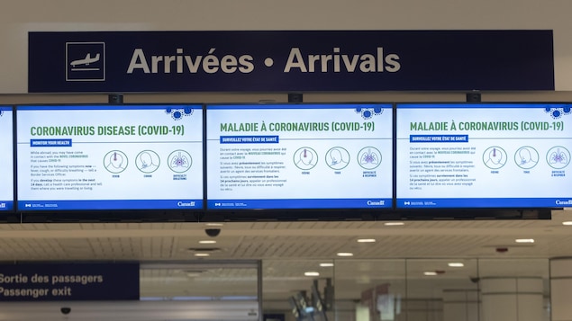 Des messages en lien avec la pandémie de la COVID-19 diffusés sur des écrans à l'aéroport de Montréal.