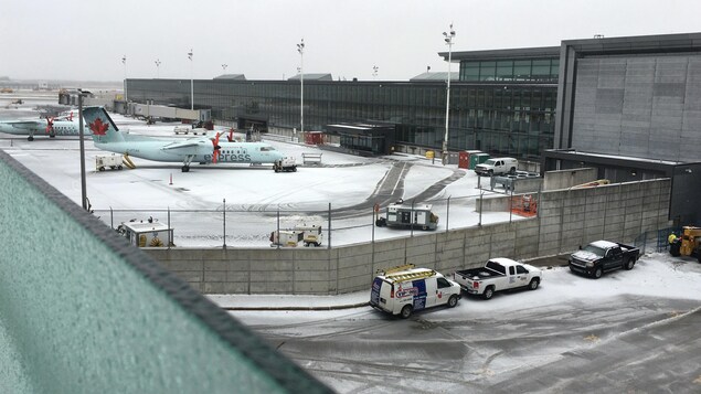 Des véhicules et des avions sont sur le tarmac à proximité du terminal.