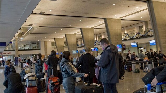 Des passagers font la file pour enregistrer leurs bagages à l'aéroport international Pierre-Elliott-Trudeau de Montréal. Des passagers font la file pour enregistrer leurs bagages à l'aéroport international Pierre-Elliott-Trudeau de Montréal.