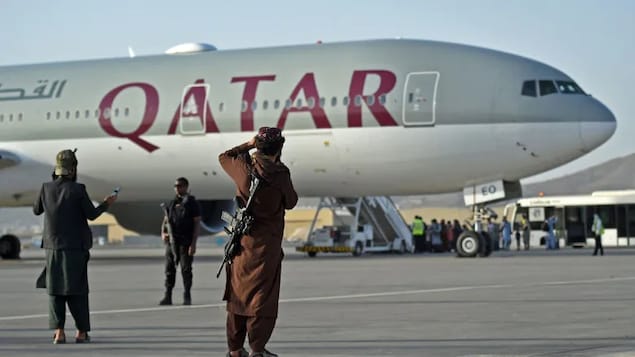 Personal de seguridad qatarí y combatientes talibanes hacen guardia mientras los pasajeros suben a un avión de Qatar Airways en el aeropuerto de Kabul el 9 de septiembre de 2021.