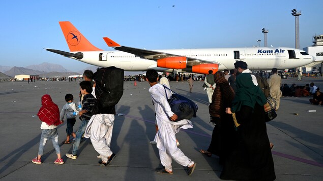 Families  during ongoing evacuations at Hamid Karzai International Airport in Kabul in August 2021. Guelph. Ont., businessman Jim Estill recently told CBC Kitchener-Waterloo's The Morning Edition he wants to sponsor 300 refugees, but the Canadian government's process rife with delays. (Sgt. Samuel Ruiz/U.S. Marine Corps/The Associated Press)