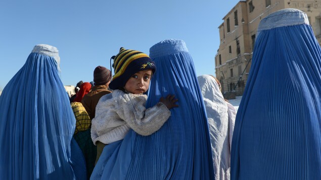 Trois Afghanes portant une burqa bleue. L'une d'elles tient dans ses bras un jeune garçon qui regarde le photographe. Trois Afghanes portant une burqa bleue. L'une d'elles tient dans ses bras un jeune garçon qui regarde le photographe.