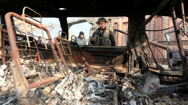 Un policier afghan inspecte une voiture qui a été incendiée