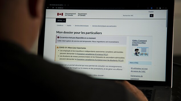 Une personne regarde le site de l'Agence du revenu du Canada sur un écran. La page lui indique qu'elle ne peut consulter son dossier de façon temporaire.
