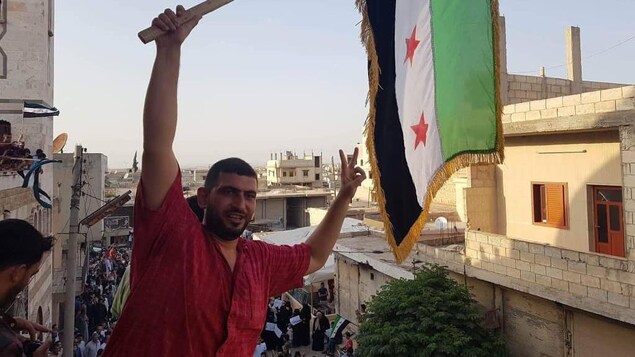 Ahmed Al Khaled brandit un drapeau syrien. Ahmed Al Khaled brandit un drapeau syrien.