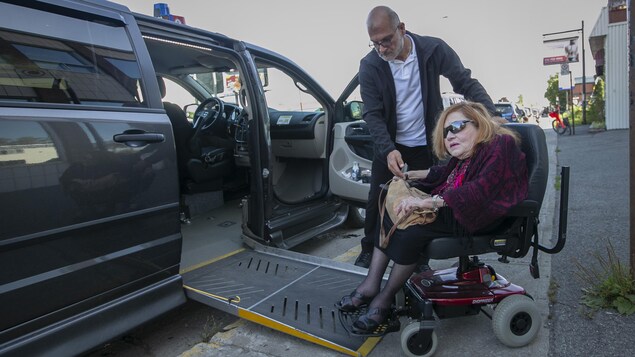 Mme Gladu sort d'un véhicule adapté pour handicapés.