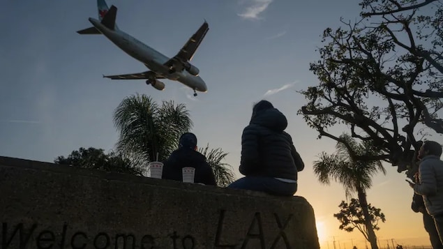Air Canada plane watched by a group of persons. The U.S. Department of Transportation is seeking $25 million in damages on behalf of U.S. customers of the airline who paid for tickets and didn't get their money back fast enough when the flights were cancelled.