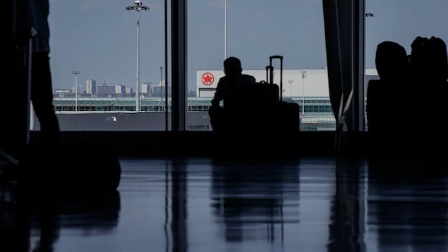 Travellers waiting around in departures at an airport.