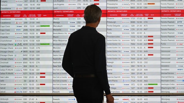 Isang lalaki tsinek ang departure board sa paliparan.