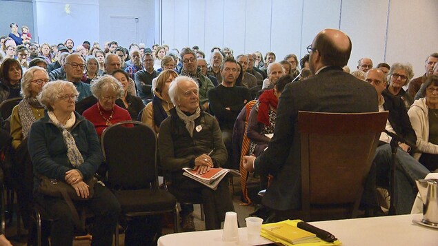 Une salle bondée de citoyens attentifs devant Alain Deneault.