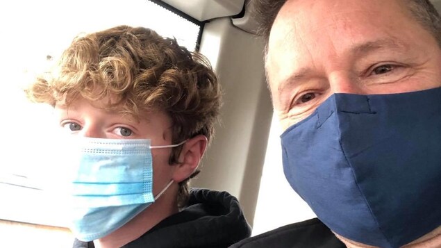Alain Lefebvre et son fils prennent un autoportrait en portant un masque dans le contexte de la pandémie.