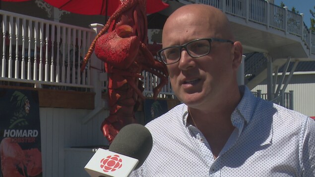 On voit un homme qui se fait interviewer par un journaliste de Radio-Canada, qu'on ne voit pas. Il se trouve devant un restaurant de homard, une figure de très grand format, représentant un homard, se trouve derrière lui. Il s'agit de Alain Renaud, un pêcheur de homard à Percé. On voit un homme qui se fait interviewer par un journaliste de Radio-Canada, qu'on ne voit pas. Il se trouve devant un restaurant de homard, une figure de très grand format, représentant un homard, se trouve derrière lui. Il s'agit de Alain Renaud, un pêcheur de homard à Percé.