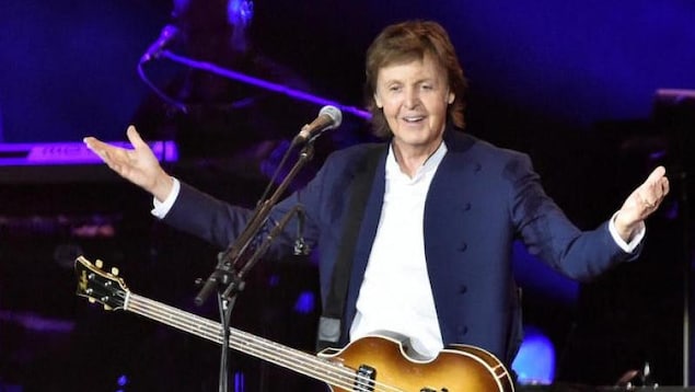 Dans la photo, le musicien a les bras ouverts avec sa guitare devant un micro. Dans la photo, le musicien a les bras ouverts avec sa guitare devant un micro.