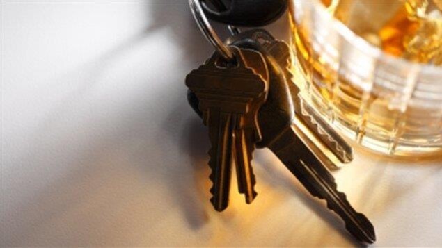 Des clés de voiture à côté d'un verre d'alcool.