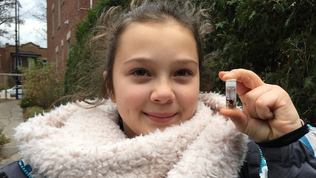 Alessandra tient un petit pot dans lequel se trouve l'araignée.