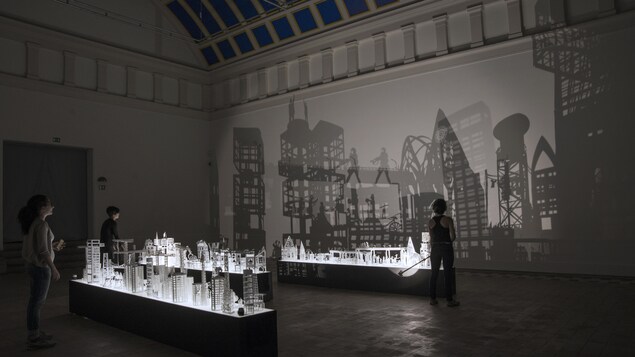 Trois personnes admirent une projection sur un mur à partir de reproductions d'oeuvres d'Alexander Calder. Trois personnes admirent une projection sur un mur à partir de reproductions d'oeuvres d'Alexander Calder.