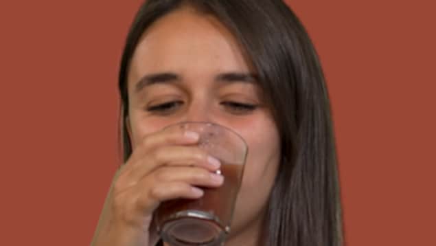 Alexnadra fortin qui boit du jus de tomate.