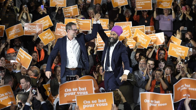Alexandre Boulerice, à gauche, lève le bras aux côtés du chef du NPD, Jagmeet Singh, durant un rassemblement partisan.