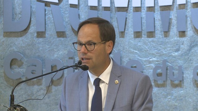 Alexandre Cusson, réélu sans opposition, présente ses priorités pour Drummondville. On le voit ici à la conférence de presse, au micro. On peut lire : « Drummondville », derrière lui.