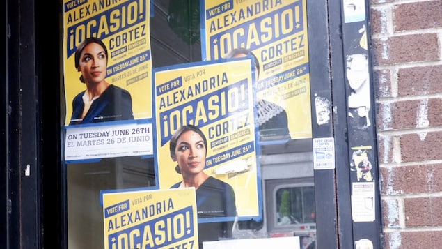 Des affiches d'une candidate politique sont placardées sur une porte vitrée.