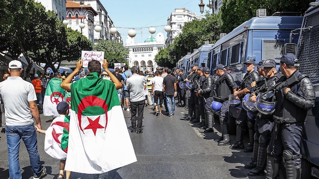 Des manifestants marchent à côté de policiers.