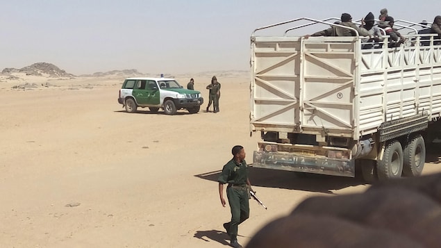 Une photo fournie par Ju Dennis, un migrant libérien, qui montre des gendarmes algériens armés chargeant des migrants sur des camions pour les déposer à la frontière nigérienne.