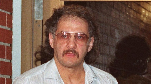 Allan Legere quitte le palais de justice les menottes aux poignets.