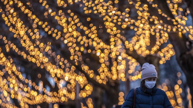 Une femme marche près d'arbres illuminés.