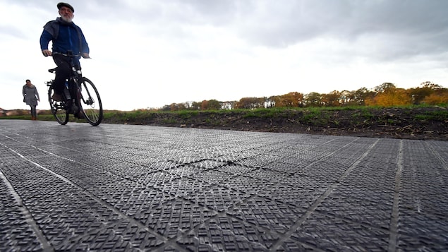 Un cycliste roule sur une piste cyclable faite de cellules photovoltaïques.